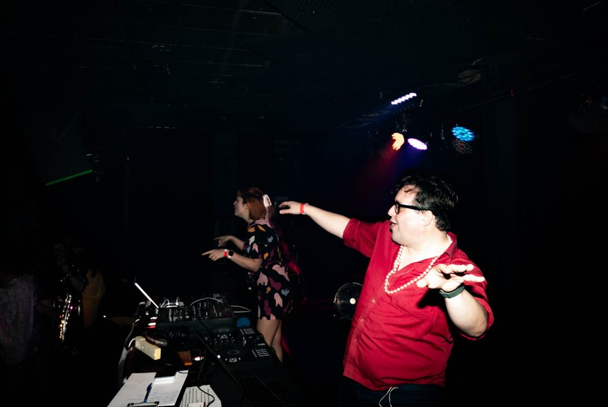 A man in a red shirt dancing at a nightclub. 