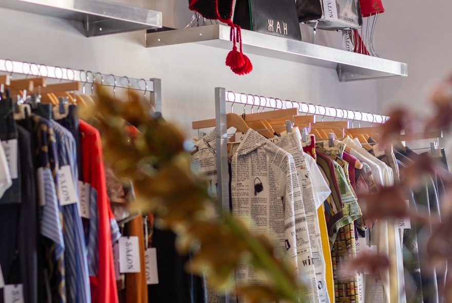 Racks of clothing on wooden hangers.