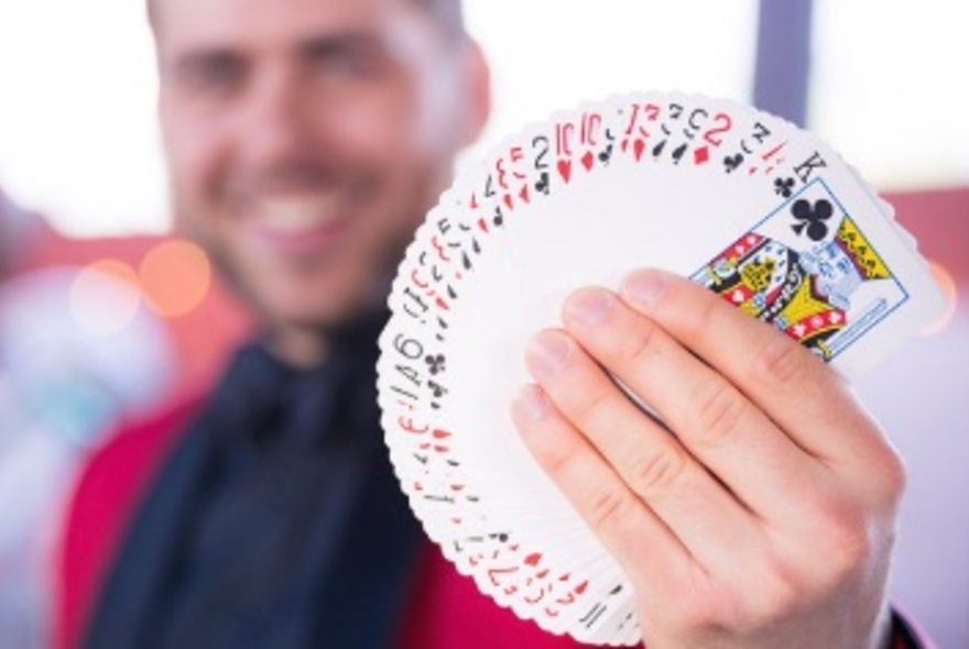 Magician, Jordy Doust, holding a fanned out deck of cards.