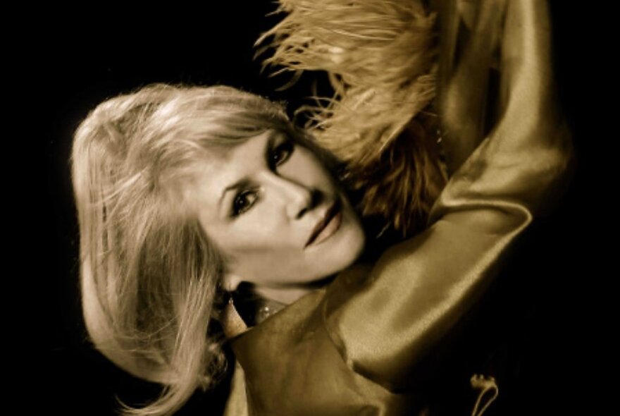 Wendy Stapleton wearing a blonde wig, make-up, feathers and satin in tribute to 1960s singer Dusty Springfirled.