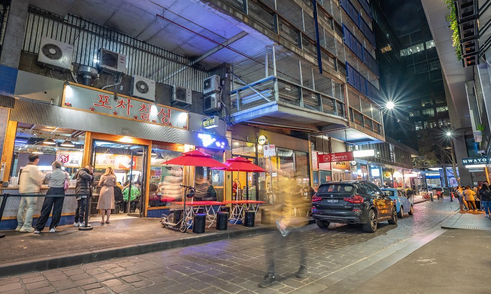 Crowds outside restaurants in a city laneway at night.