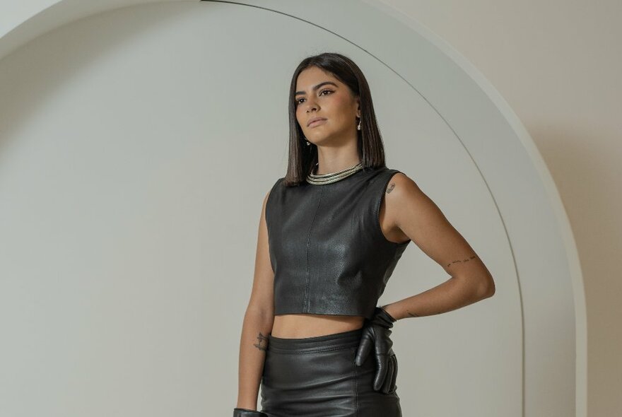 A model wearing a black leather sleeveless top and skirt.