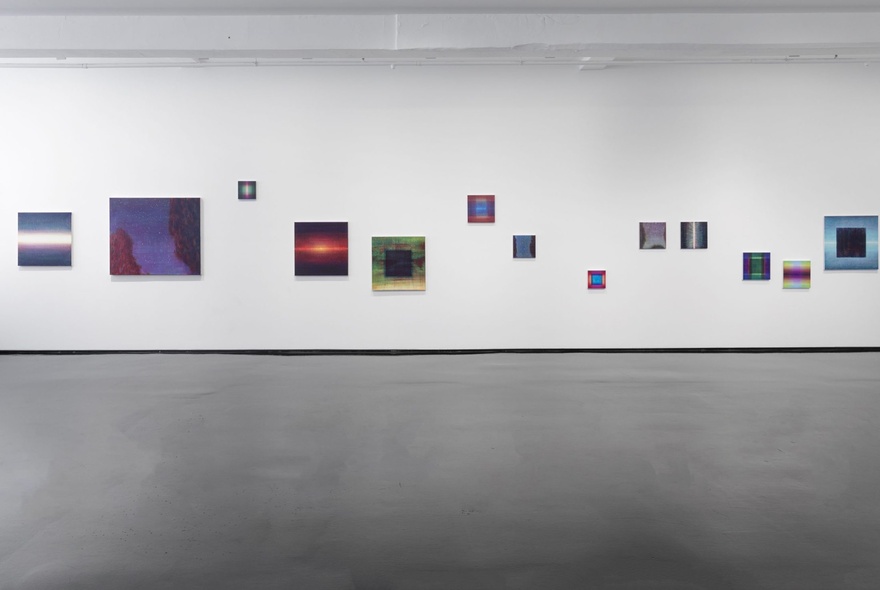 A gallery wall with an array of small paintings in a random arrangement. 
