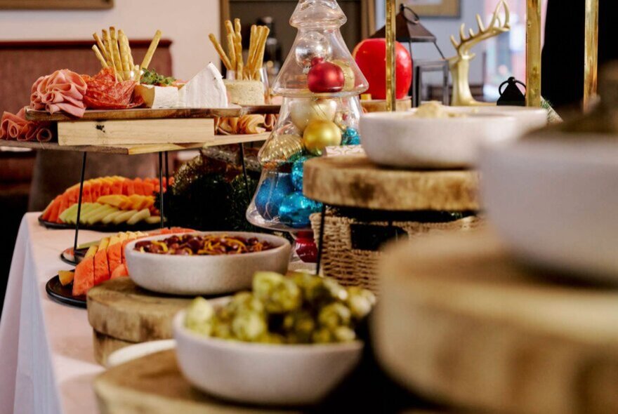 A restaurant buffet with bowls and platters of food arranged on a table covered in white linen with festive decorations.
