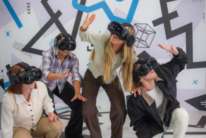 Four people crouched and with their hands in front of them, all wearing VR headsets, taking part in the Machu Picchu: Journey to the Lost City virtual reality experience.