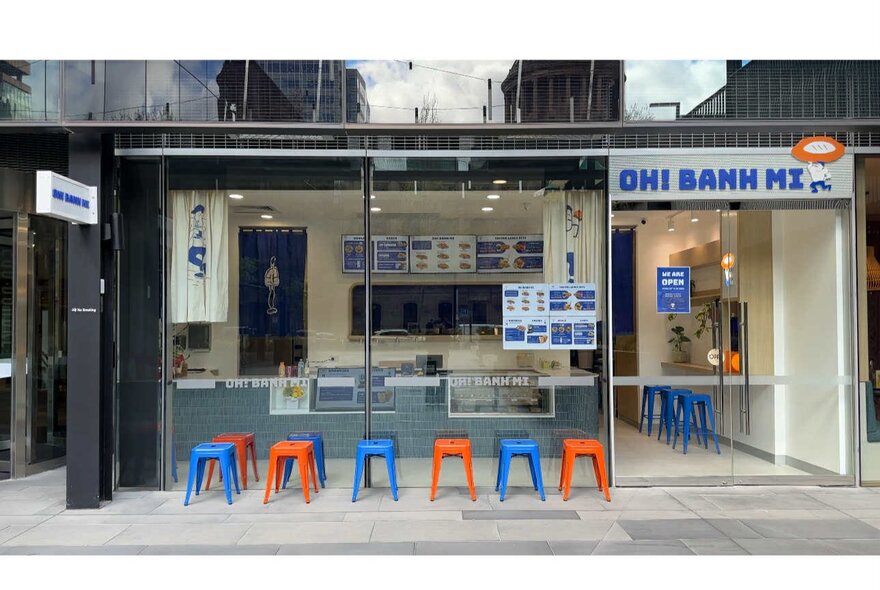 Red and blue stools lined up outside takeaway banh mi shop.