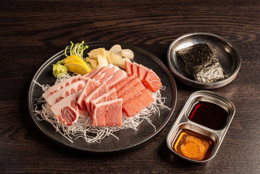 Small pieces of raw Waygu beef arranged on a tray with dipping sauces.