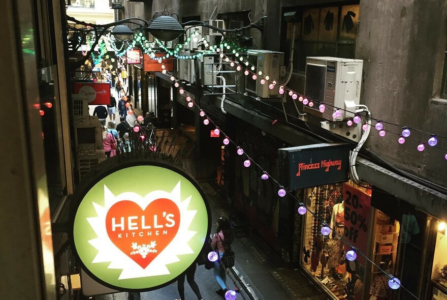 Night view looking down on the illuminated Hell's Kitchen sign and laneway below.