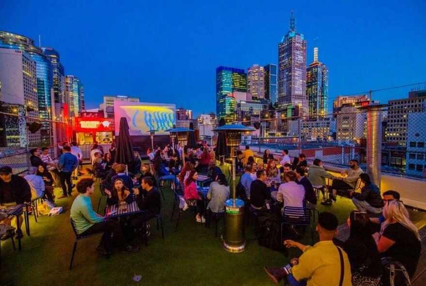 A group of people sitting at a rooftop bar