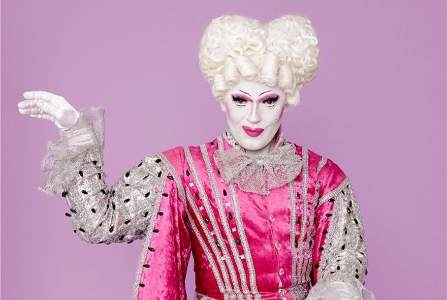 Performer wearing pink satin 18th-century costume with white wig and makeup.