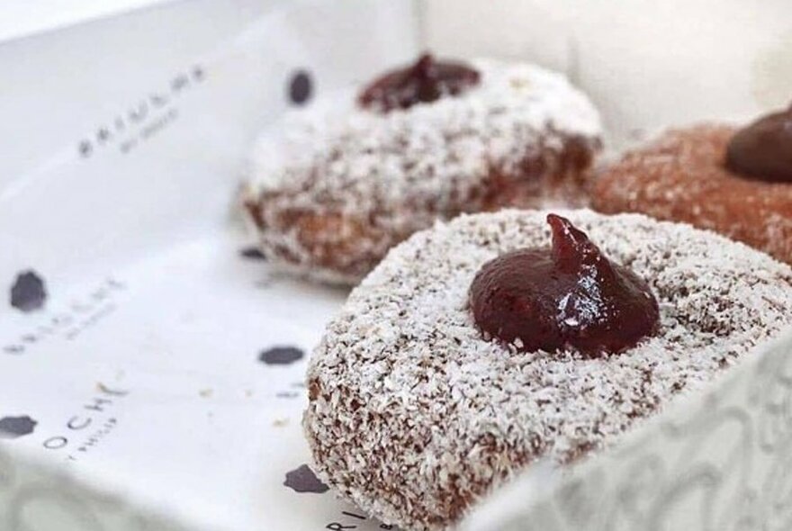 Three lamington-style doughnuts in a box.