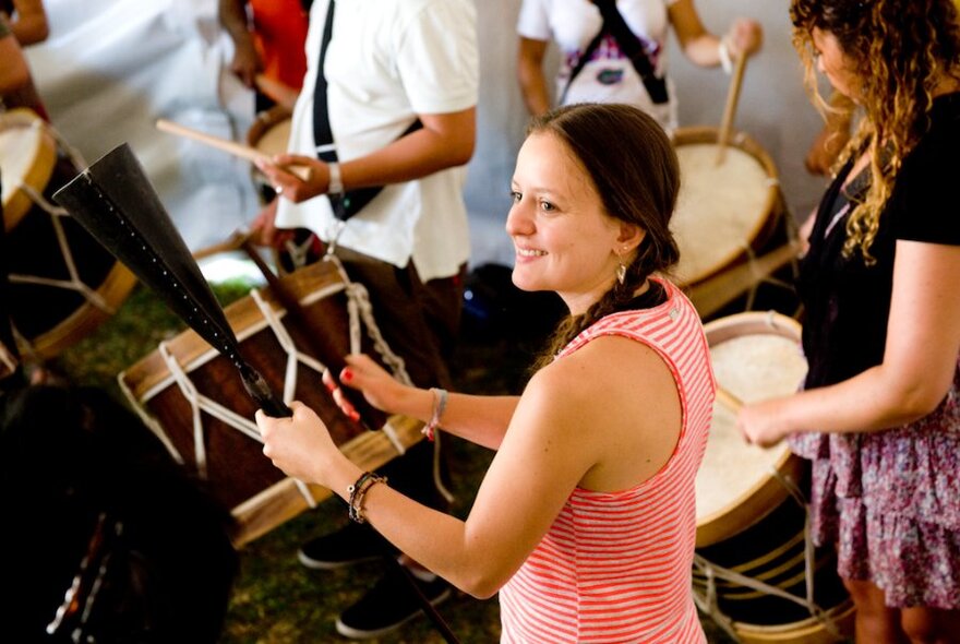 A woman looks happy as she holds a drum. 