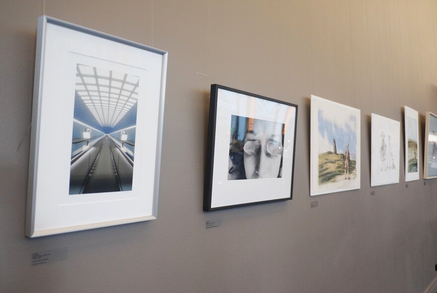 A wall with a display of framed art in a gallery setting. 