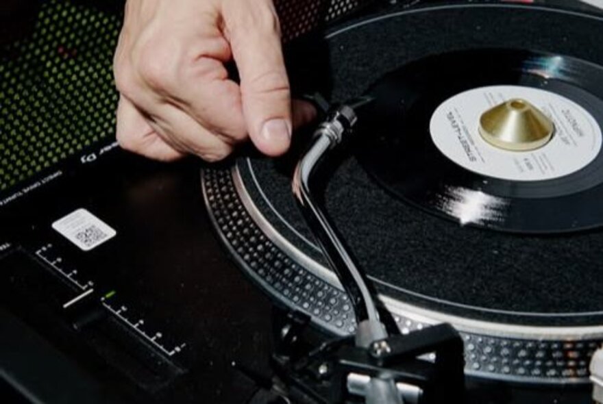 Hand placing the stylus on a record.