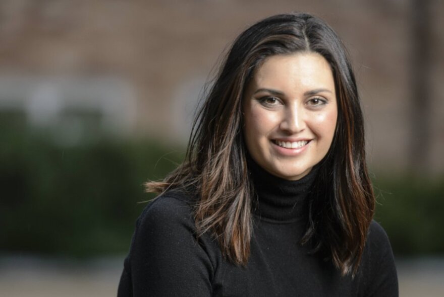 Jamila Rizvi smiling warmly and wearing a black turtleneck jumper. 