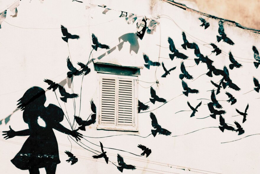 Wall stencil of a girl releasing birds on strings.
