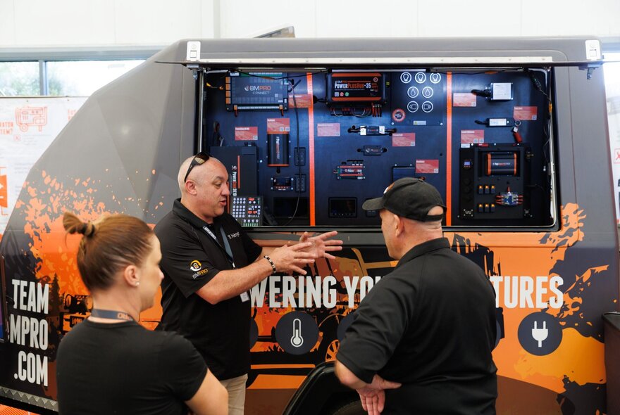 A salesperson talking to two customers about power options for camping.