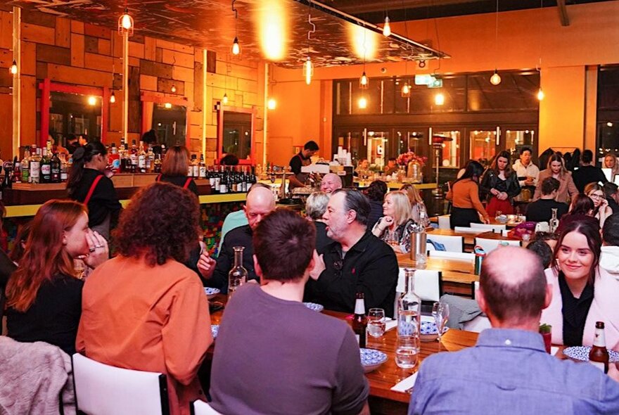 People dining and drinking in a full restaurant. 