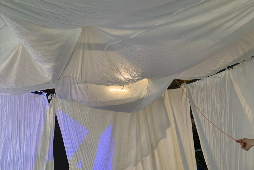 Installation showing white sheets hanging together with blue and clear lights cast on them.