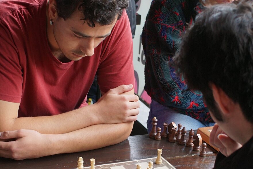 Two people playing chess at a table, concentrating on the game.