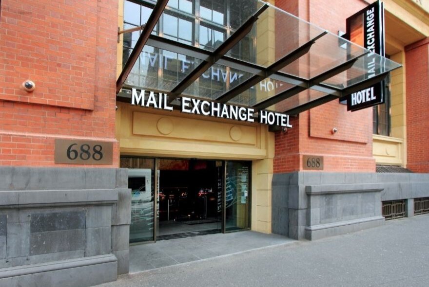 Exterior of the Mail Exchange Hotel building of red bricks, with footpath visible.