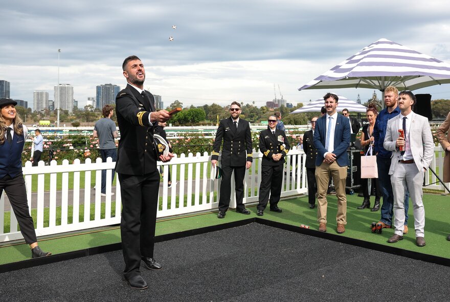 People tossing a coin, playing two-up during Anzac Day celebrations at Flemington Racecourse.