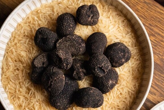 Looking down at a bowl of whole black truffles.