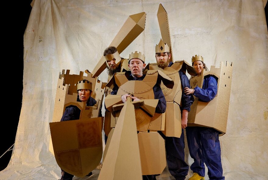 Actors from Back to Back Theatre dressed in cardboard costumes, posing in front of a white sheet.