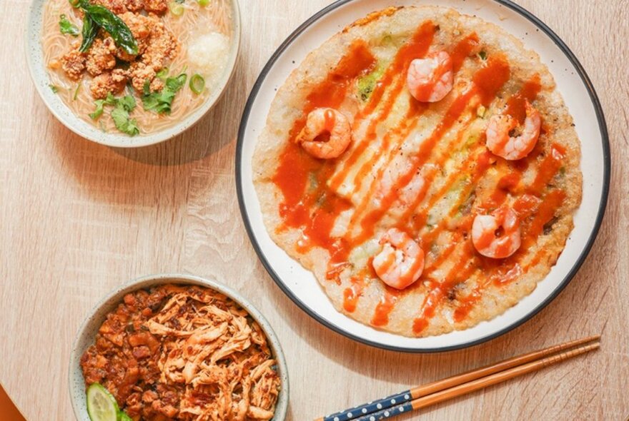 Dishes on a table with chopsticks including rice with prawns.