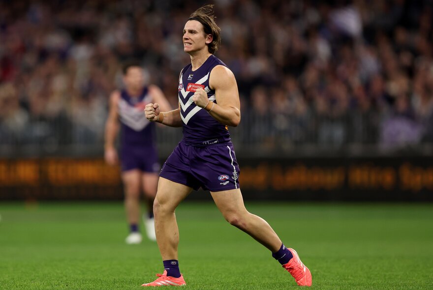 A Fremantle Dockers AFL player pumping his fists in celebration during a game.