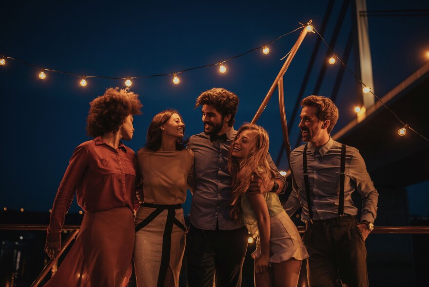 People hugging under lights on a boat at night.