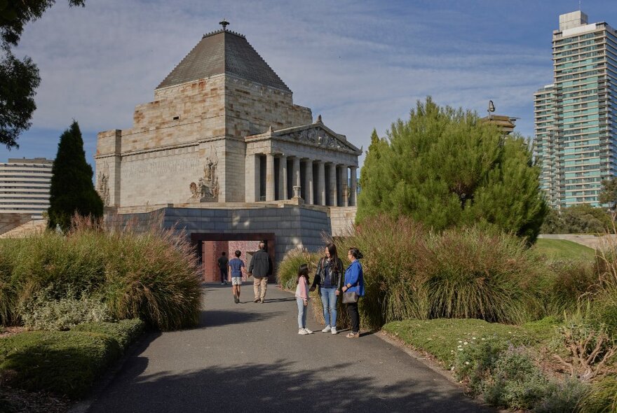 The view of Melbourne's Shrine of Remembrance from a pathway through the Shrine gardens; people walking and standing on the path.
