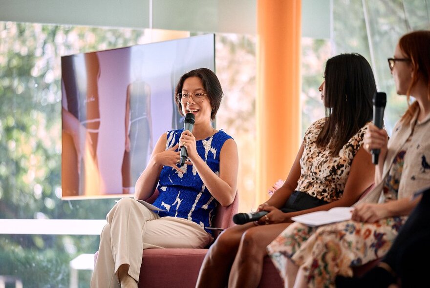 Three seated people holding microphones, interacting and talking at a panel event as part of the Paypal Melbourne Fashion Festival.