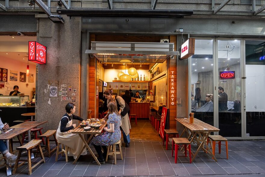 Warmly lit laneway restaurant with outdoor seating.