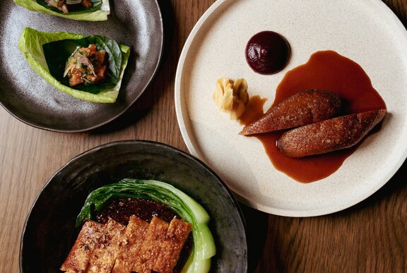 Looking down at a fine dining dish featuring duck breast with a spiced sauce and garnishes.