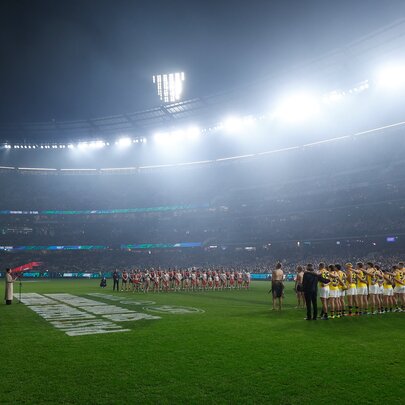 Misty lights on the oval as AFL football players line up before a game.