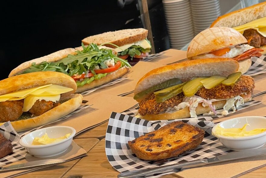 Table laid with plates of food including filled panini rolls.