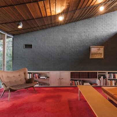 The retro interior of a 1950s home with red carpet and amber chairs. 