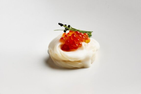 A small appetiser like a white cloud nest with orange caviar and garnish