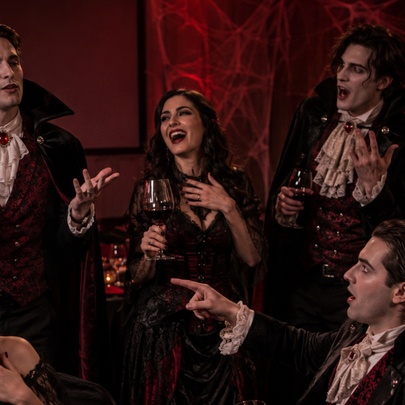A group of people dressed in Dracula themed costumes all holding wine glasses.