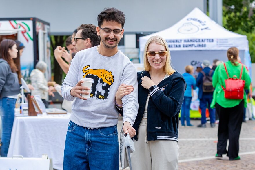 A smiling young couple at an outdoor market.