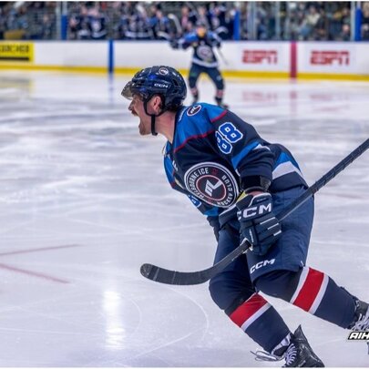 An ice hockey player in blue, skating on an ice hockey rink.