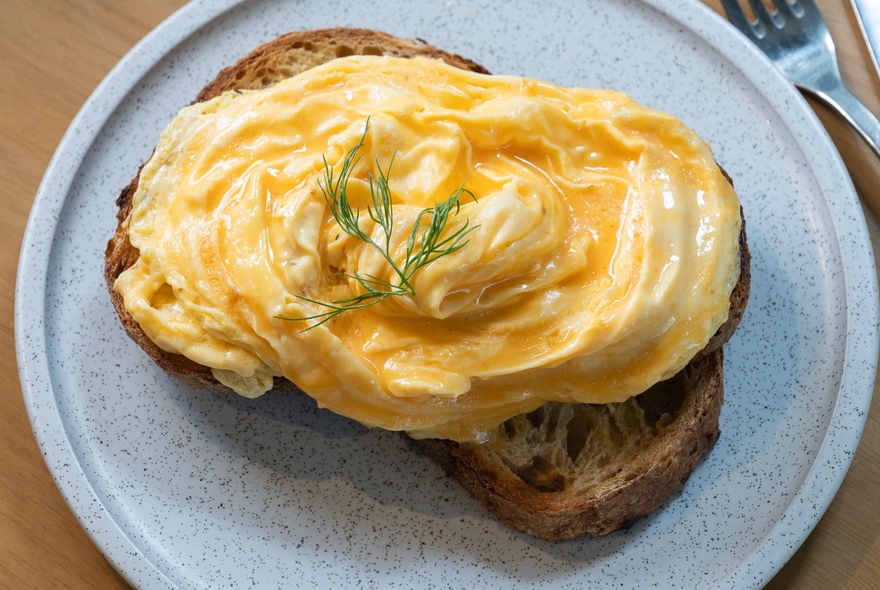 Creamy scrambled eggs served on toast on a white plate.