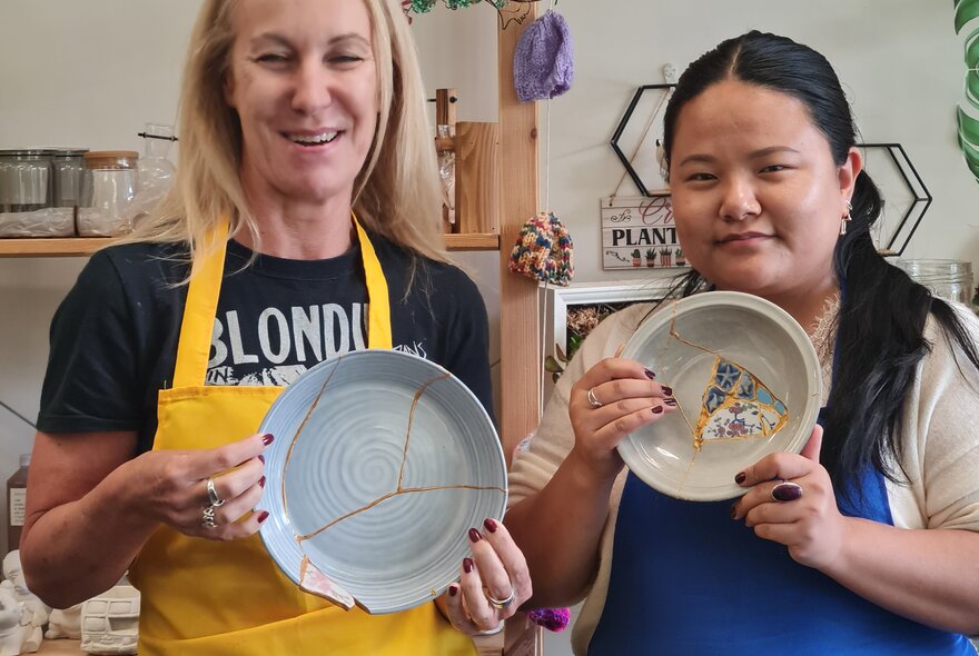 Person holding a broken plate mended with gold glue and mismatched patterned inset.