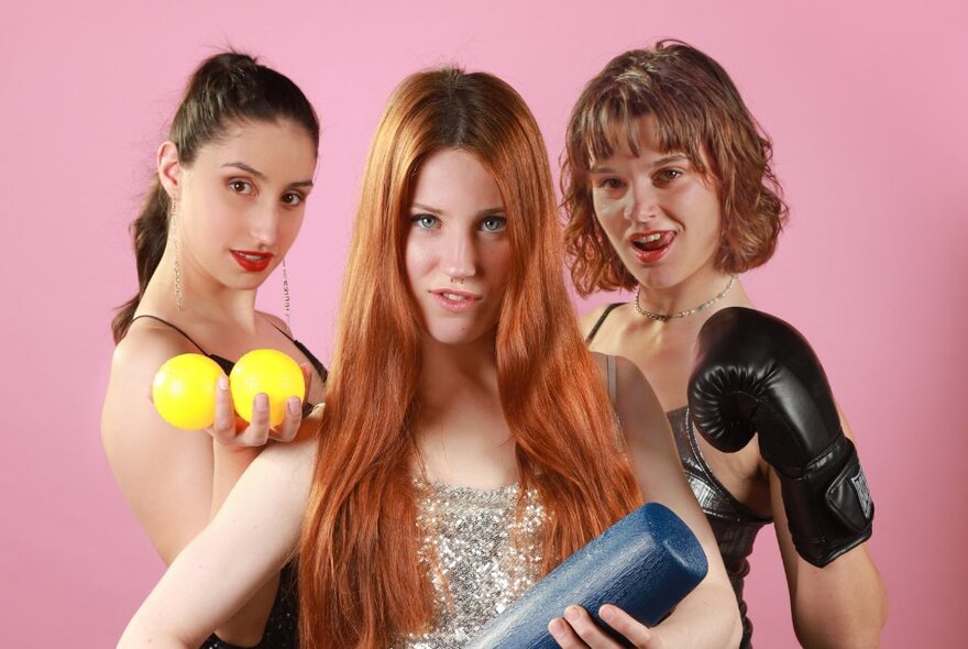 Three comedians standing with sports props - tennis balls, a club and boxing gloves.