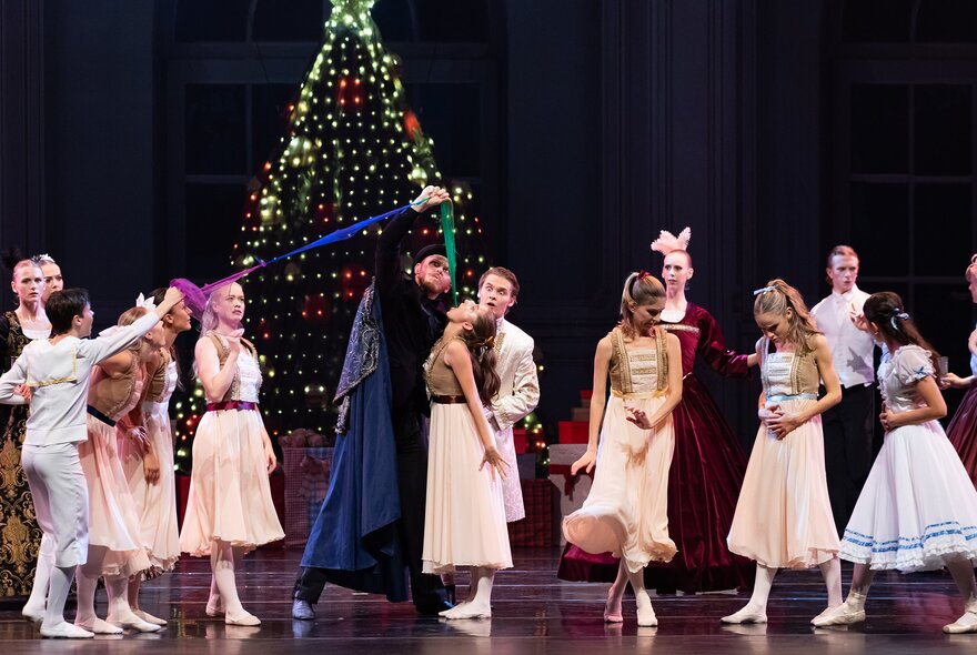Dancers performing on stage in front of a Christmas tree.
