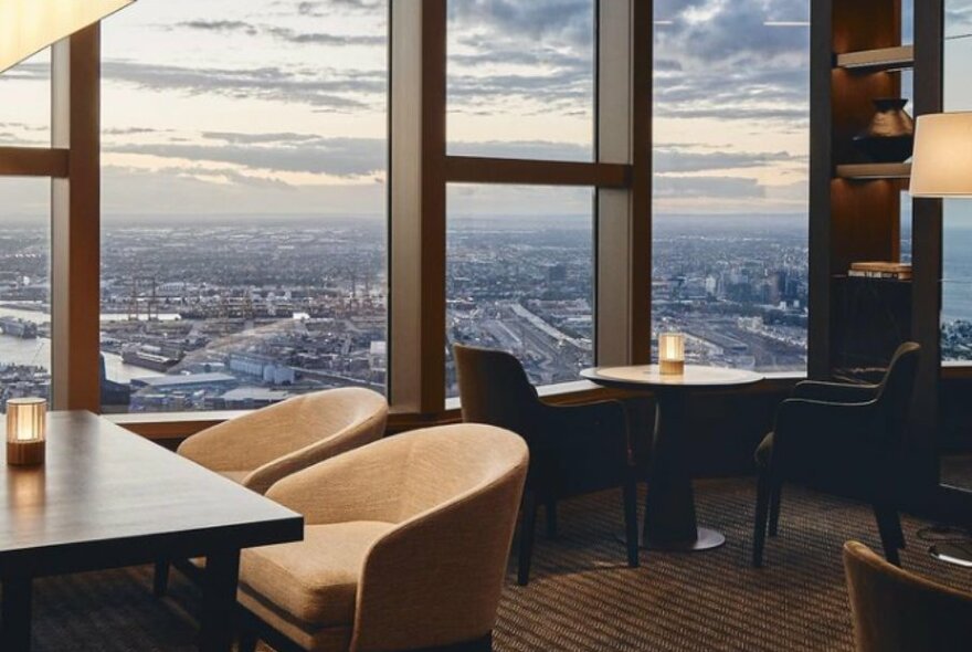 Dining room in a high rise building with large windows and small groups of tables.