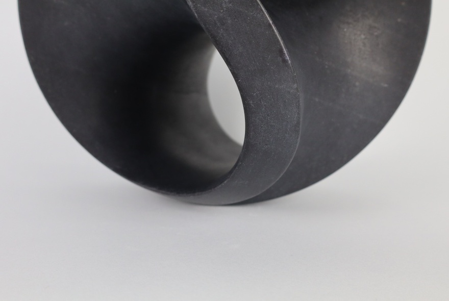 Smooth-textured, curved black abstract sculpture.