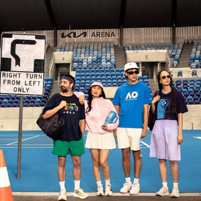 Four fashion models posing in Australian Open tennis-inspired clothing with a tennis stadium in the background, and distinctive Melbourne road signs in the foreground.