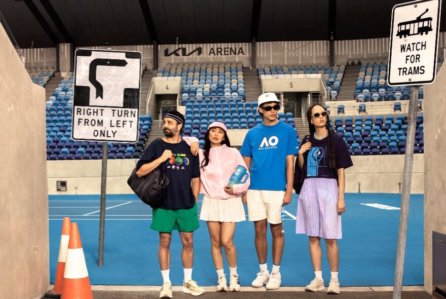 Four fashion models posing in Australian Open tennis-inspired clothing with a tennis stadium in the background, and distinctive Melbourne road signs in the foreground.